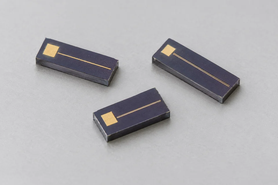 Representative compact bare laser dies with gold contact pads and cleaved semiconductor facets